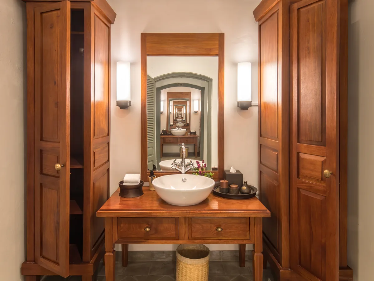 Badezimmerdetail mit Holzschrank, Steinwaschbecken und warmem Seitenlicht