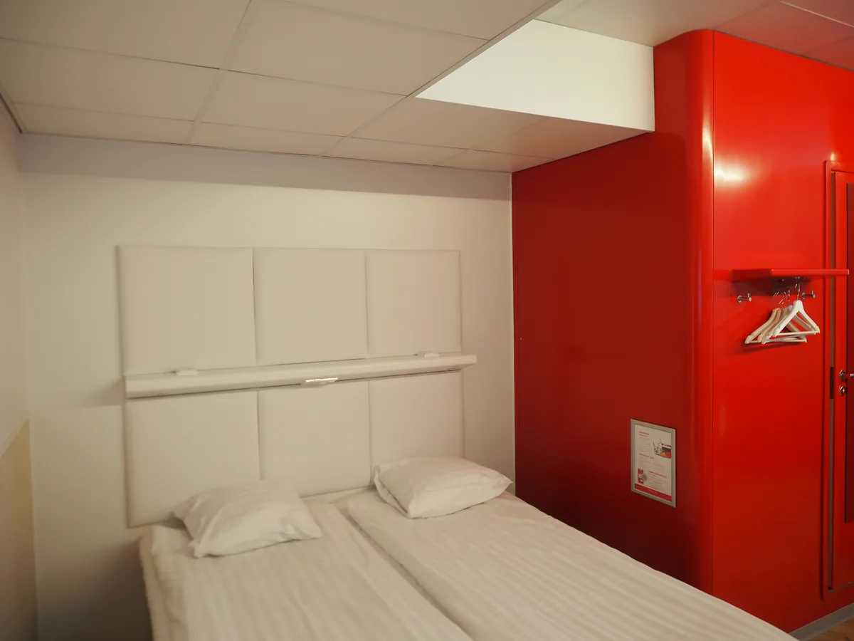 Deluxe Room mit Kingsize-Bett, dunklem Kopfteil und warmer Zimmerbeleuchtung