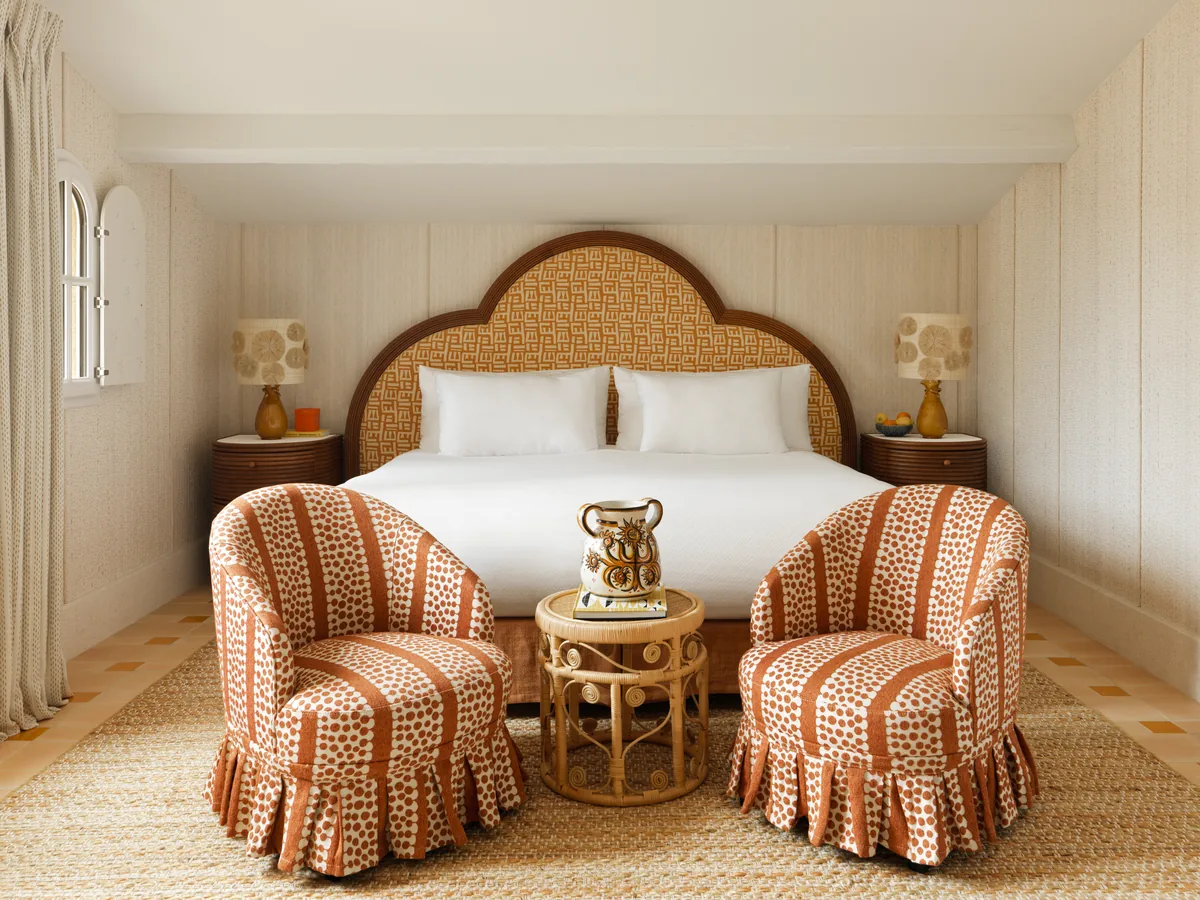 Junior Suite mit Bett, zwei Sesseln am Fenster und warmen Stofffarben
