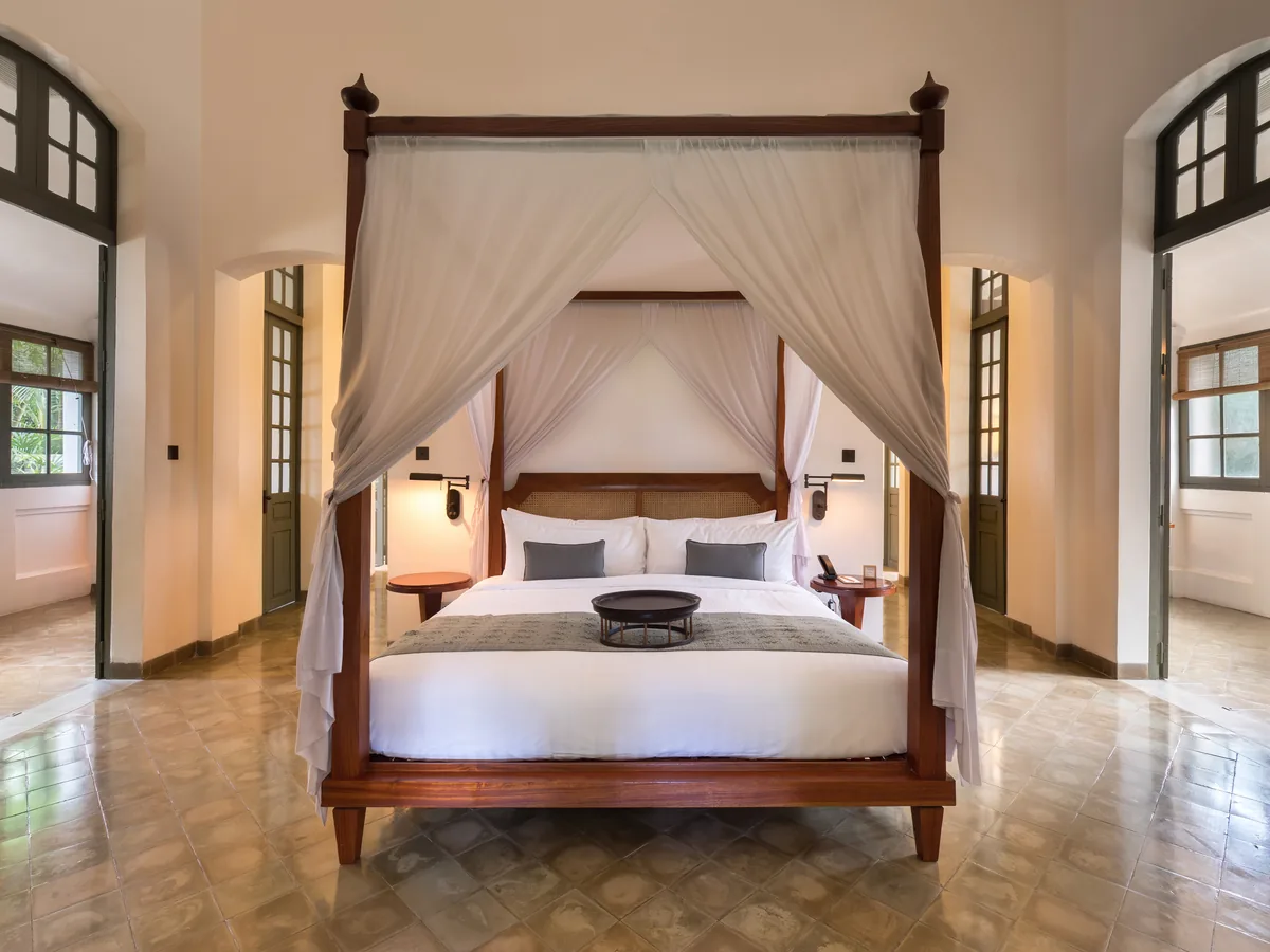 Luxury Suite mit Himmelbett aus dunklem Holz und offenem Wohnbereich