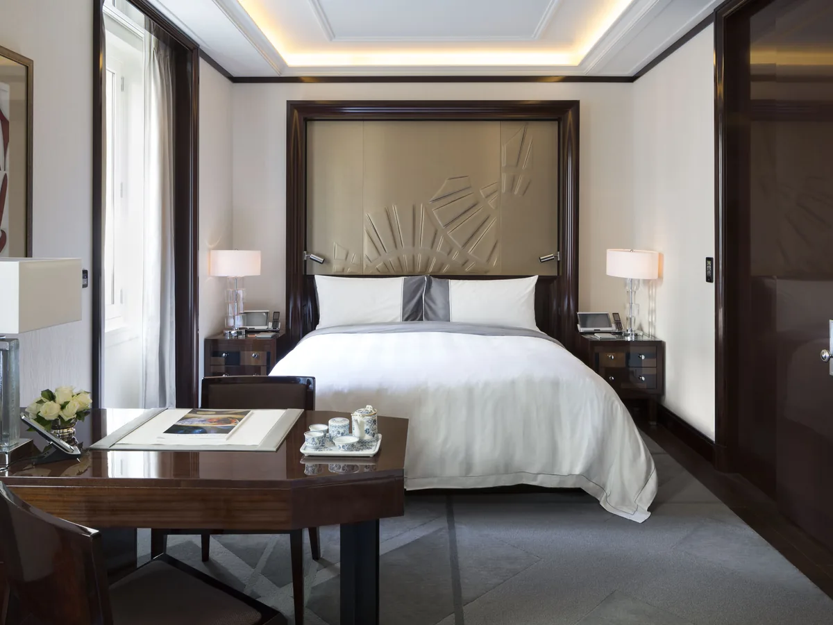 Premium Room mit hohem Kopfteil, hellen Vorhängen und Blick über die Dächer