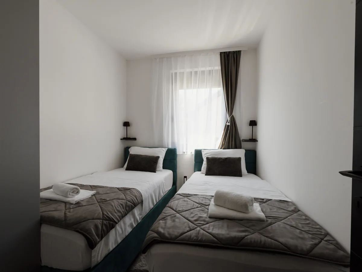 Standard Room mit zwei hellen Betten, weißem Leinen und puristischem Interieur