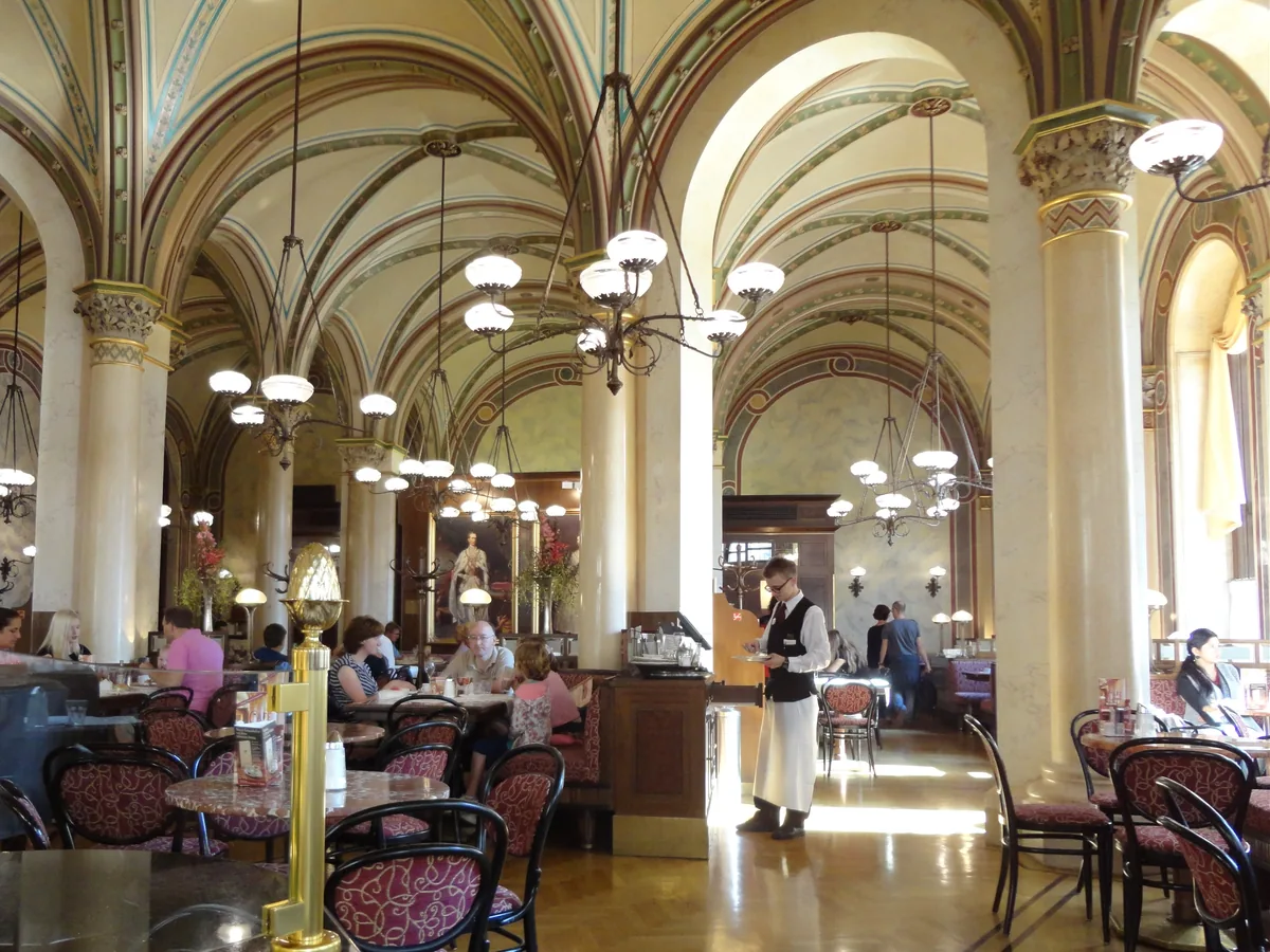 Gewölbter Lounge-Bereich mit Marmorsäulen und Café-Stühlen